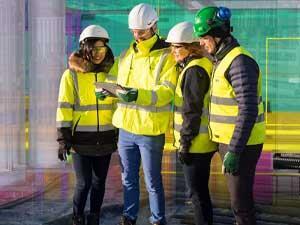 Construction team onsite gather round tablet to compare Trimble Connect model to actual built environment